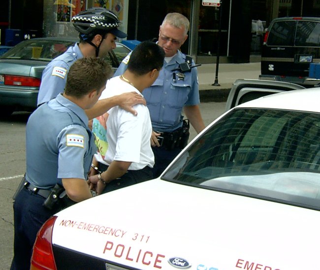 Three policemen taking a Latino man into custody