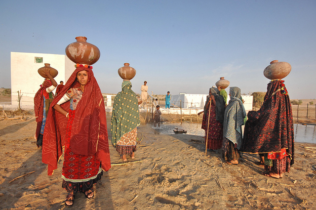 Women with bowls on their head to fill up with water gathered at the Somo Samo village well