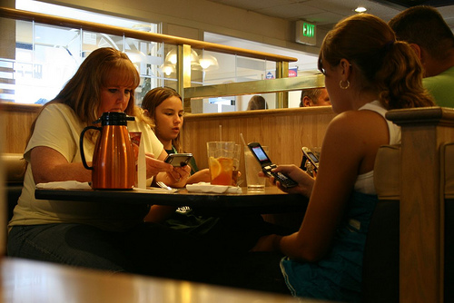 A family sitting at a table, all engrossed in their phone