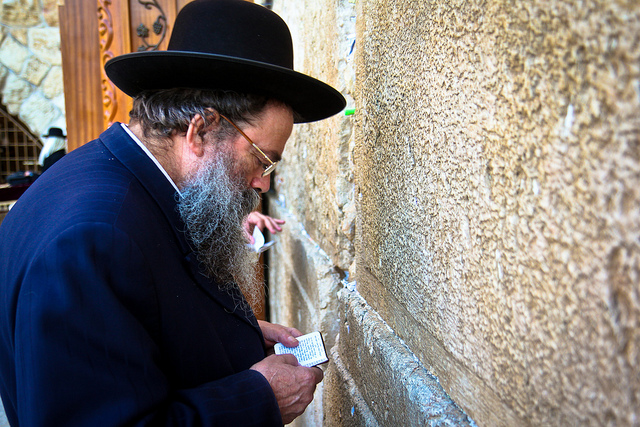 A jewish man placing his prayer note in a wall