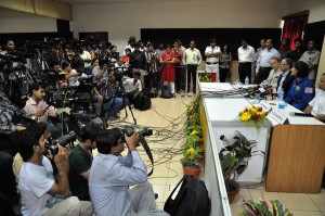 A press conference with a sea of reporters and cameras