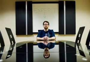 A man sitting at the head of business table. He is the expert