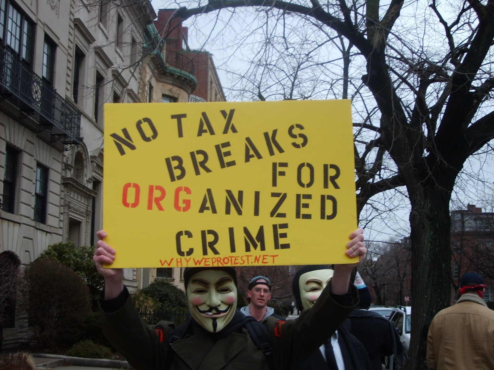 An anonymous demonstration with a man holding a sign saying:
