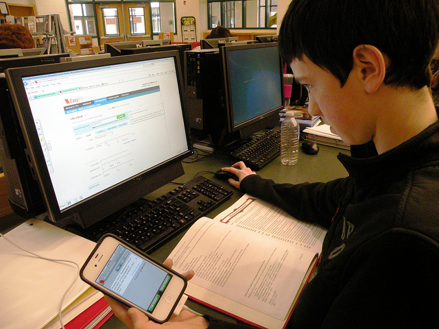 A student using a computer and a phone to study