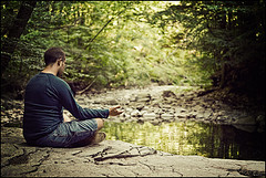 A man meditating in the woods by a pond