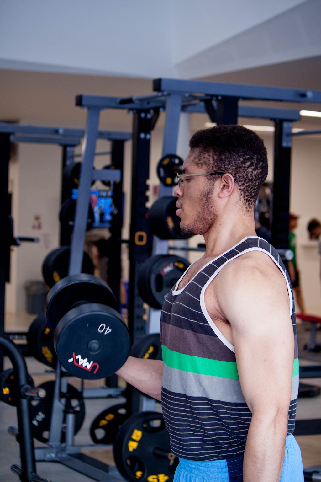 A man lifting a 40 pound dumbbell in a gym setting.