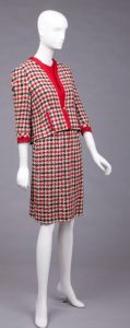 mannequin wearing a signature Chanel style of 1955 - three pieces composed of a jacket, skirt, and a coordinating blouse in a red checkered pattern
