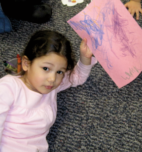 Preschooler holding piece of paper with scribbling/writing
