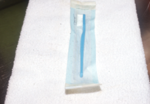 a blue toothbrush in a plastic bag laying on a white towel