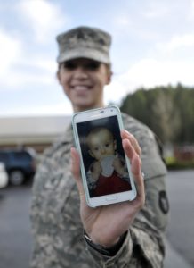 Soldier showing a picture of her child on a smartphone.