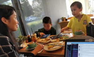 A family eating breakfast together. A computer open to Slack is in the corner.