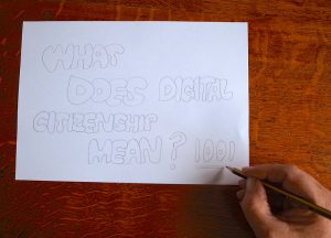 Paper on a wooden table that says, 'What does digital citizenship mean? 1001'