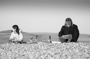 Child with a man using an iPad outside.