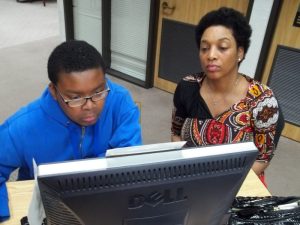 Younger child and older woman looking at a computer screen.