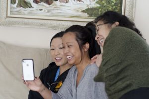 Three women smiling and looking at a phone.