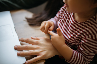 Little girl with her mom looking at laptop together. Arms closeup