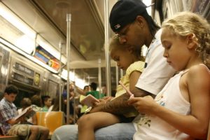 A child with her family playing a videogame on the subway.