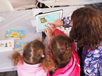 Young children looking at a tablet screen with an older woman.