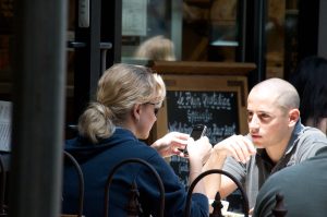 Couple sitting at a table. The woman is looking at her phone.