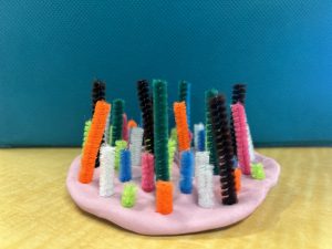 pink playdough pancake with colorful pipe cleaners sticking up