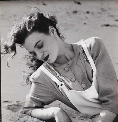 Image of woman reclined on beach wearing a white apron