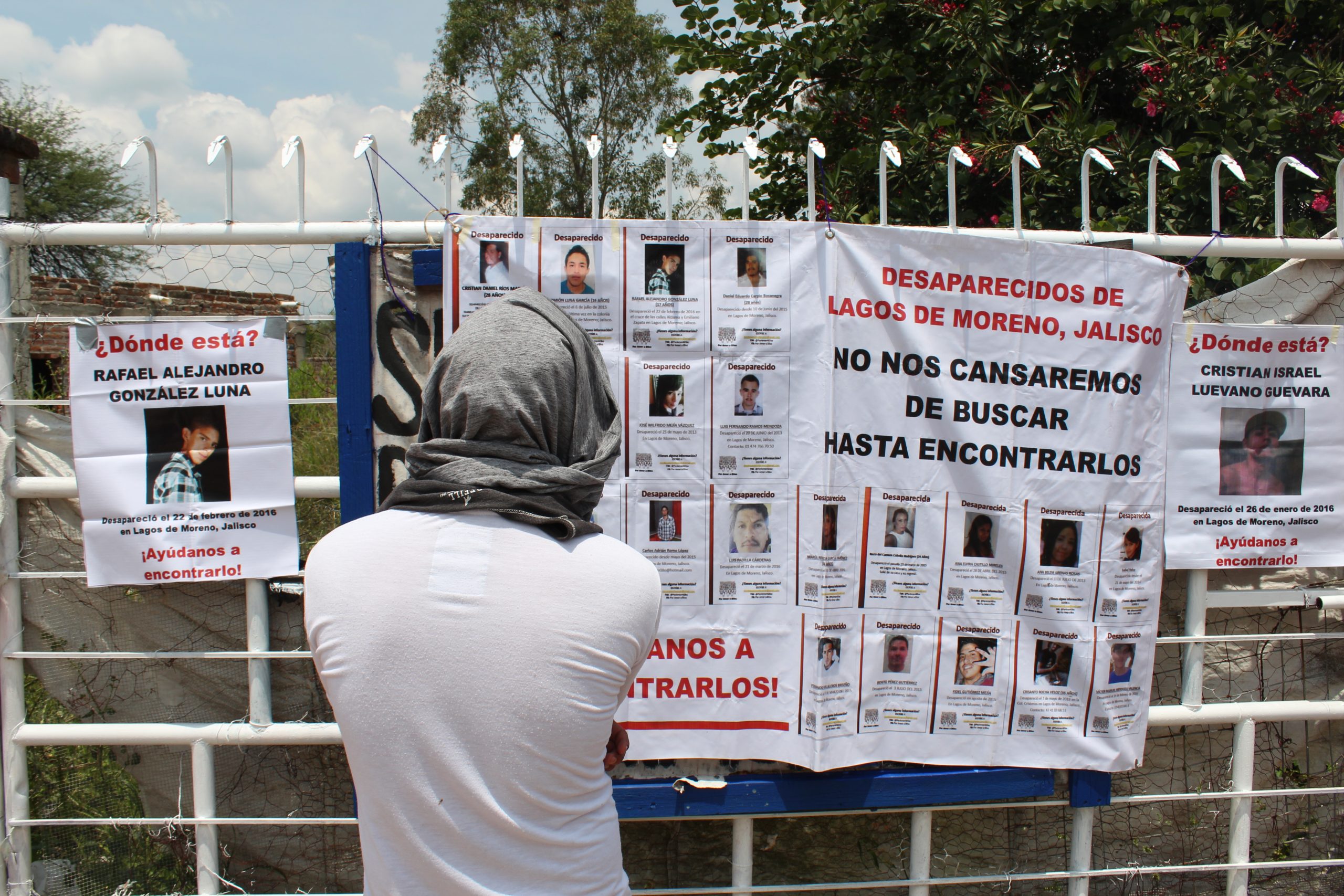 Una persona mira carteles de personas desaparecidas con títulos como "No nos cansaremos de buscar hasta encontrarlos"