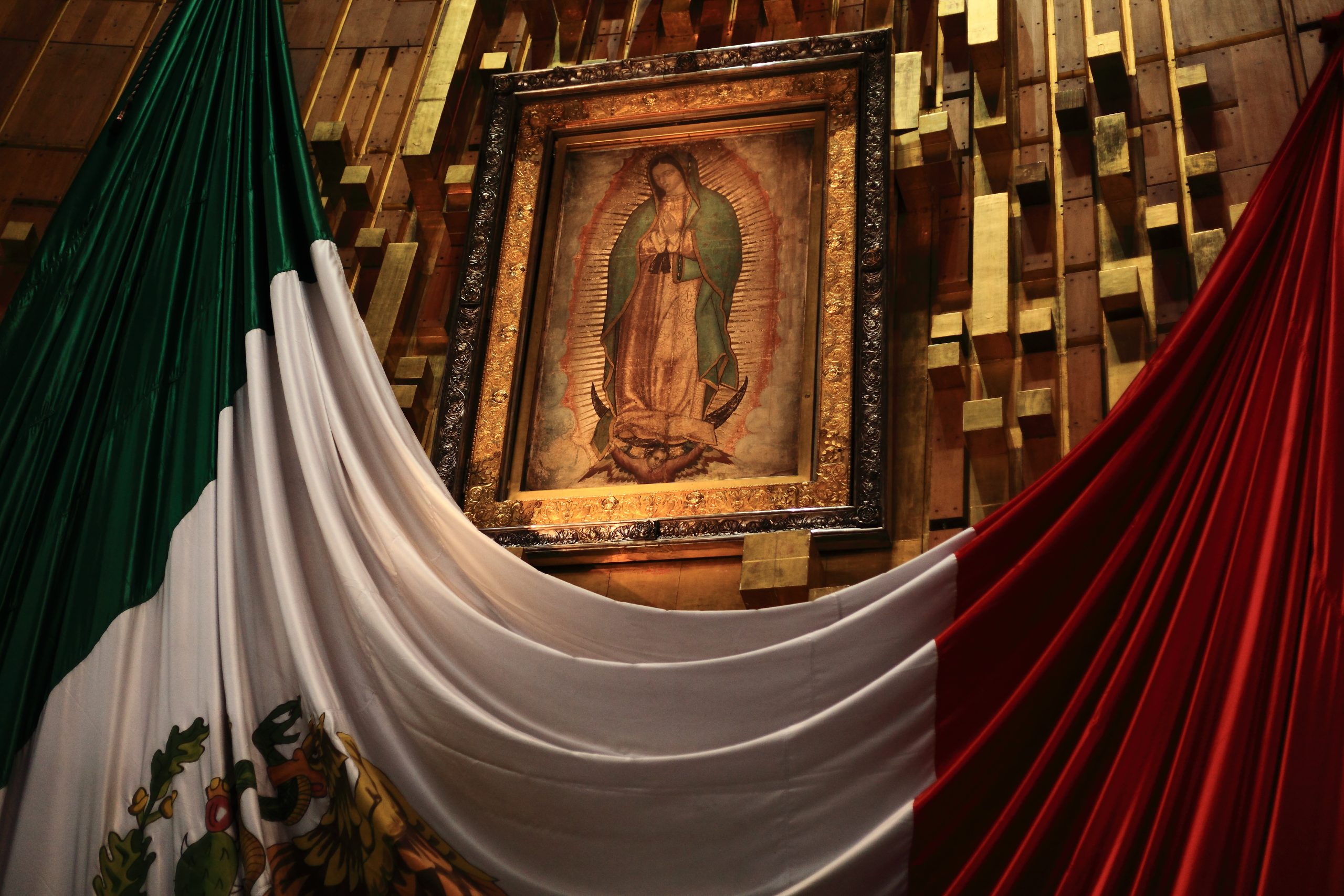 Picture of the Virgen de Guadalupe with a Mexican flag draped beneath.
