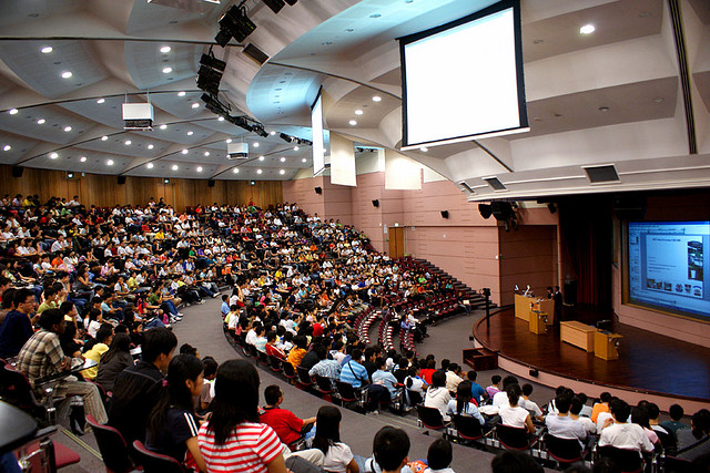 A giant lecture hall using the visual aids of a large projector and a TV